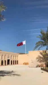 cour intérieure avec drapeau du qatar blanc et marron flottant sous ciel bleu