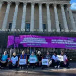 manifestants devant l'assemblée nationale avec bannière violette pour la solidarité