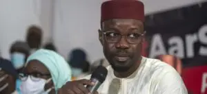 homme en tenue traditionnelle sénégalaise tenant un microphone lors d'un discours public