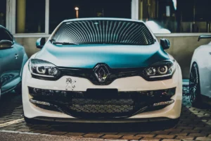 renault blanche avec grille noire et logo diamant, stationnée de face la nuit